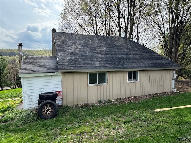 view of property exterior featuring roof with shingles and a yard
