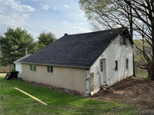 view of side of property featuring a lawn and a shingled roof