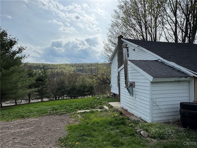 view of side of home with a shingled roof