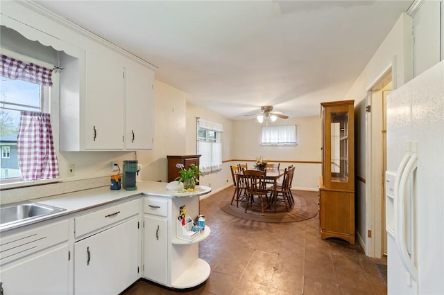 kitchen featuring light countertops, white cabinetry, a ceiling fan, and white refrigerator with ice dispenser