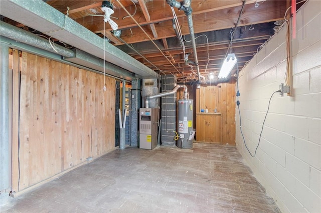 unfinished below grade area featuring concrete block wall, heating unit, and water heater