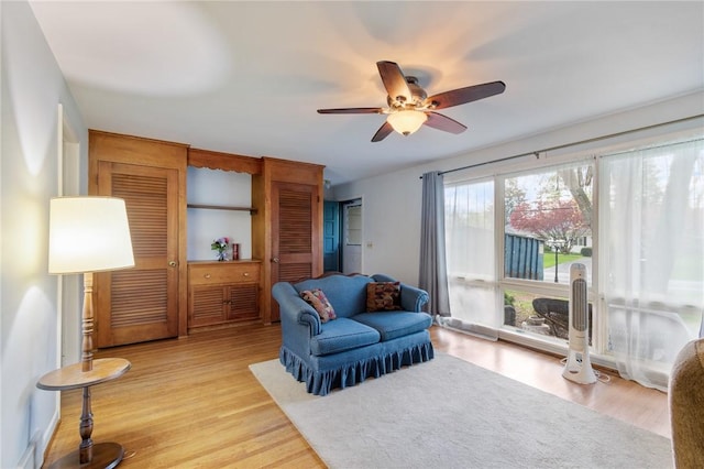 living area with ceiling fan and light wood-style flooring