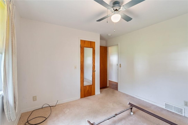 carpeted empty room with visible vents, a ceiling fan, and baseboards