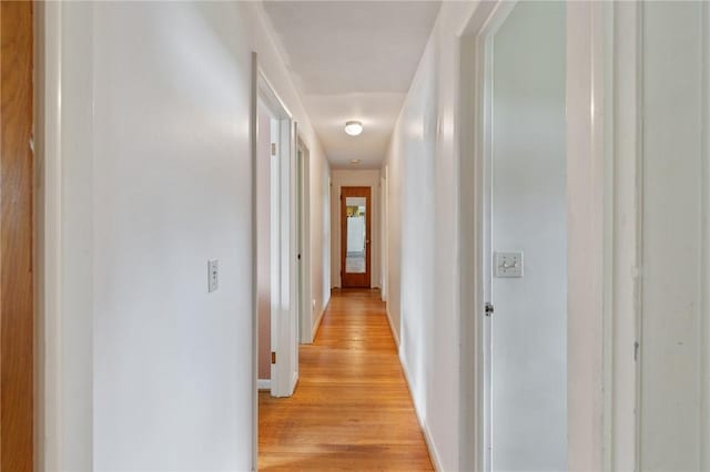 hallway with light wood-type flooring and baseboards