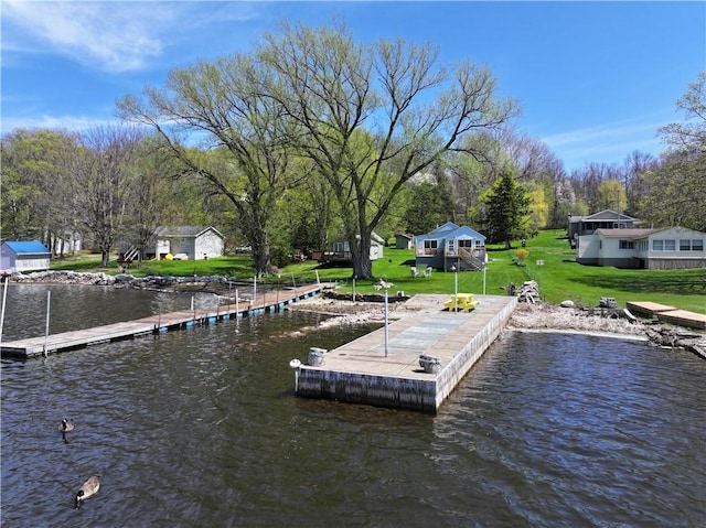 view of dock featuring a lawn and a water view