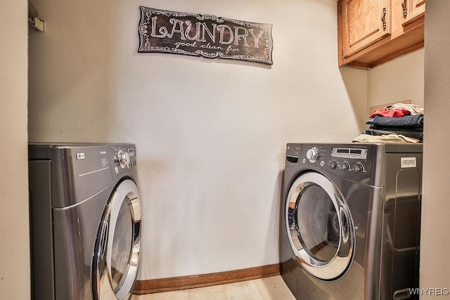 washroom with baseboards, cabinet space, and washer and dryer