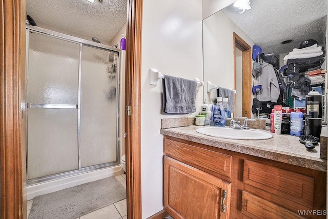 bathroom featuring vanity, a textured ceiling, tile patterned floors, and a stall shower