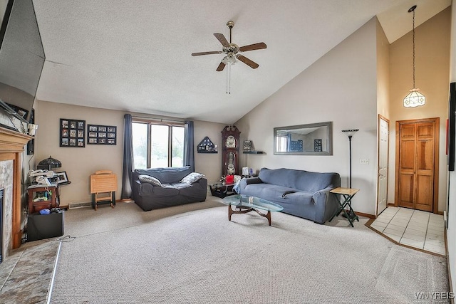 living area with ceiling fan, a glass covered fireplace, light carpet, and high vaulted ceiling