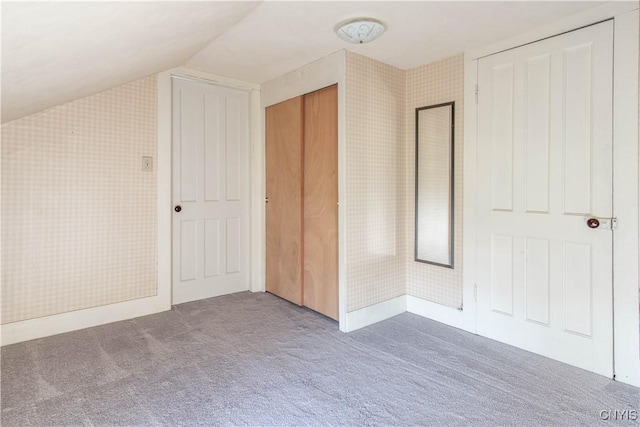 unfurnished bedroom with carpet, vaulted ceiling, and wallpapered walls