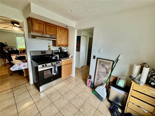 kitchen with a textured ceiling, electric stove, a ceiling fan, light tile patterned floors, and under cabinet range hood