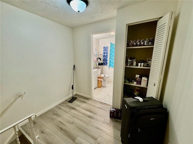washroom with a textured ceiling, baseboards, and light wood-type flooring