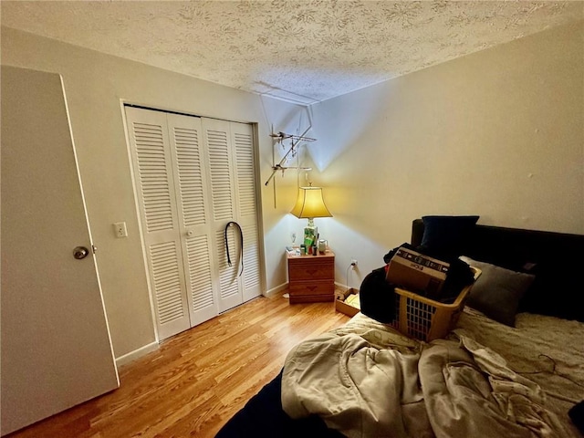 bedroom with a textured ceiling, baseboards, a closet, and wood finished floors