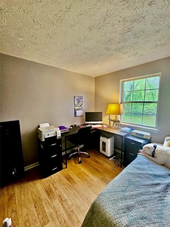 bedroom with a textured ceiling and wood finished floors