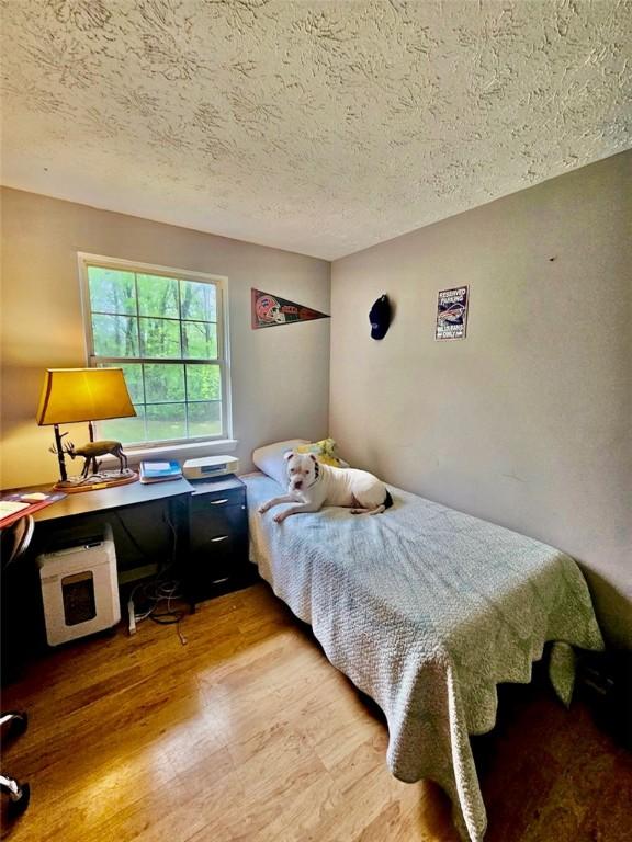bedroom with a textured ceiling and wood finished floors