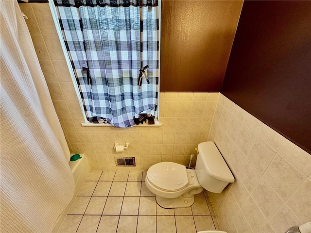 bathroom featuring tile patterned flooring, shower / bath combo with shower curtain, visible vents, toilet, and tile walls