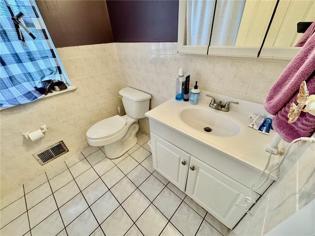 bathroom featuring visible vents, vanity, toilet, tile walls, and tile patterned floors
