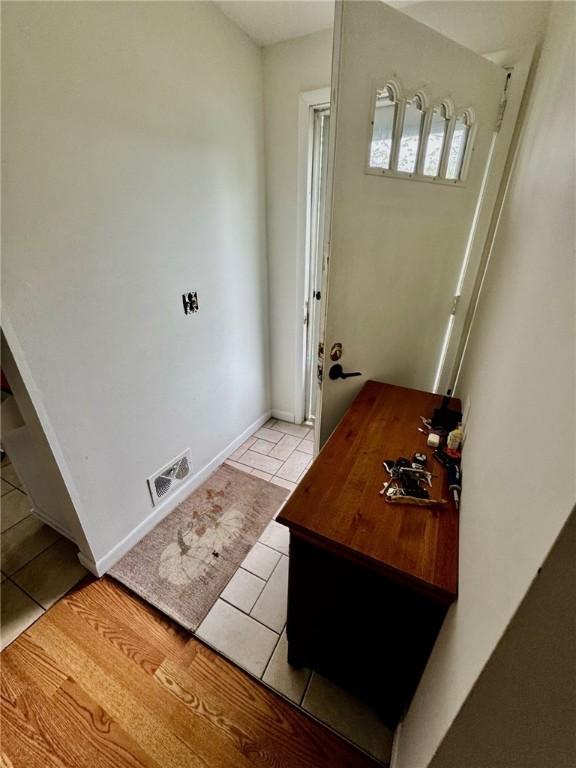 doorway with baseboards, visible vents, and light tile patterned floors