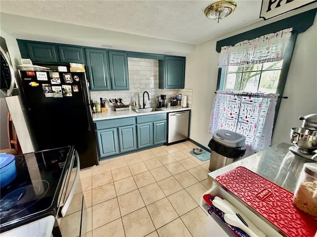 kitchen featuring a sink, dishwasher, light countertops, range with electric cooktop, and freestanding refrigerator