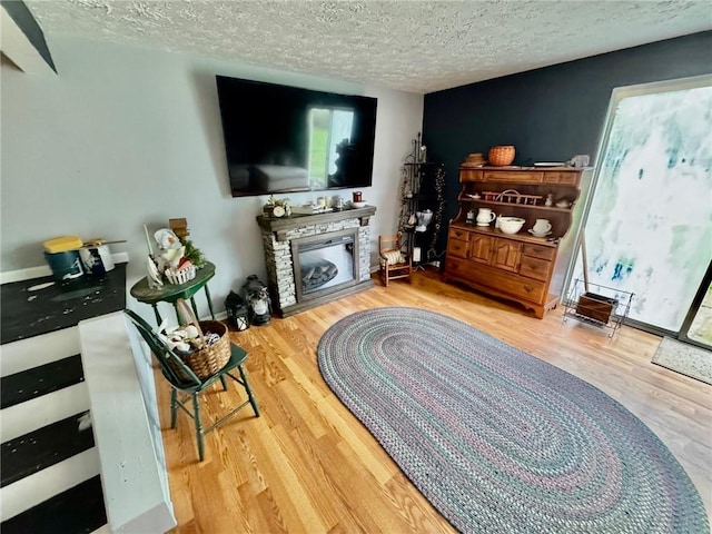 living area featuring a textured ceiling, wood finished floors, and a fireplace