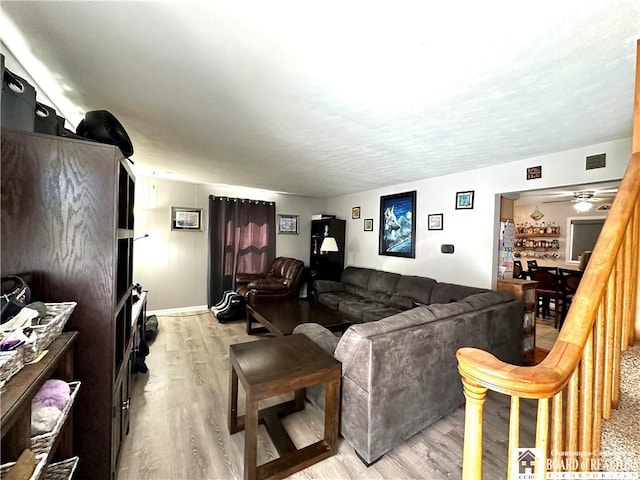 living room featuring a ceiling fan, baseboards, visible vents, and light wood-type flooring