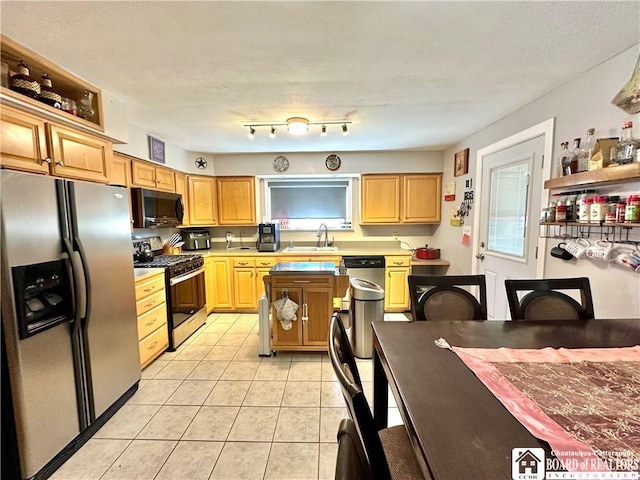 kitchen with a sink, light countertops, light tile patterned floors, and stainless steel appliances