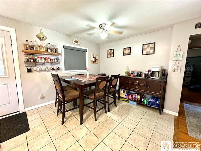 dining area with baseboards, ceiling fan, light tile patterned flooring, and a bar