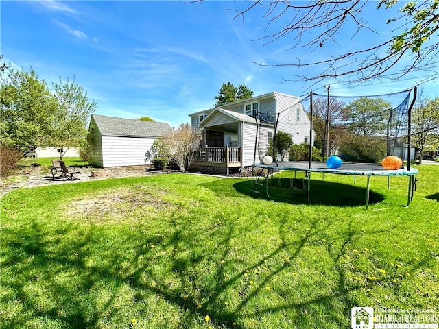 view of yard with a trampoline, a shed, an outbuilding, and a deck