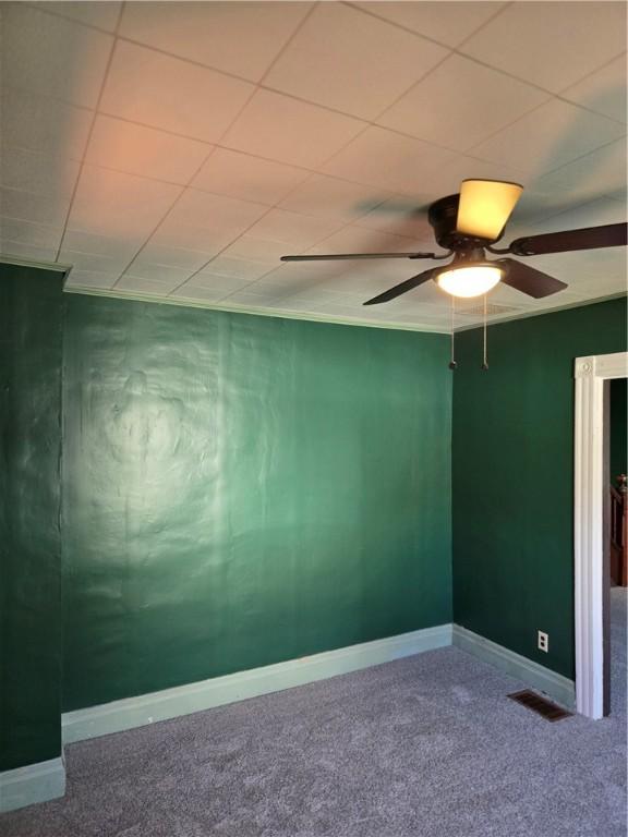 empty room with baseboards, ceiling fan, carpet, and visible vents