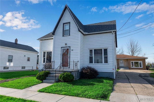 view of front of home featuring a front lawn and roof with shingles