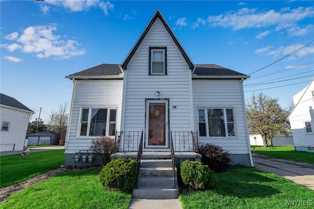 view of front of property featuring roof with shingles and a front yard