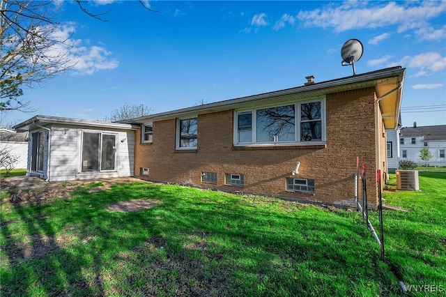 rear view of property with a lawn, brick siding, and central AC