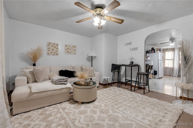 living room with arched walkways and a ceiling fan