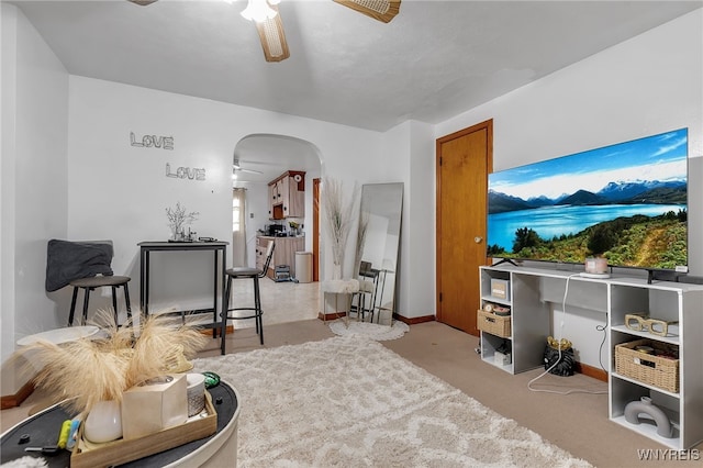 sitting room with arched walkways, baseboards, and a ceiling fan