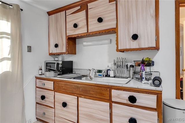 kitchen featuring light countertops, a sink, and light brown cabinets