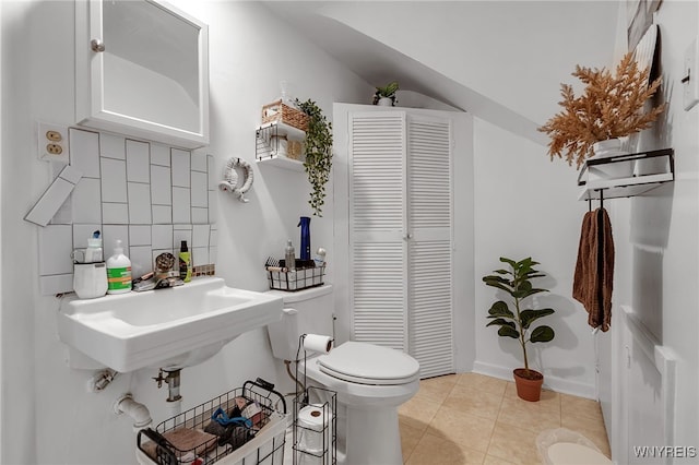 bathroom featuring backsplash, tile patterned flooring, a sink, a closet, and toilet