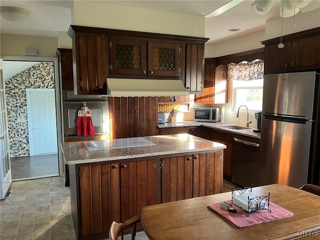 kitchen with dark brown cabinets, range hood, a center island, a sink, and stainless steel appliances