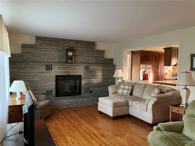 living area featuring a stone fireplace and wood finished floors