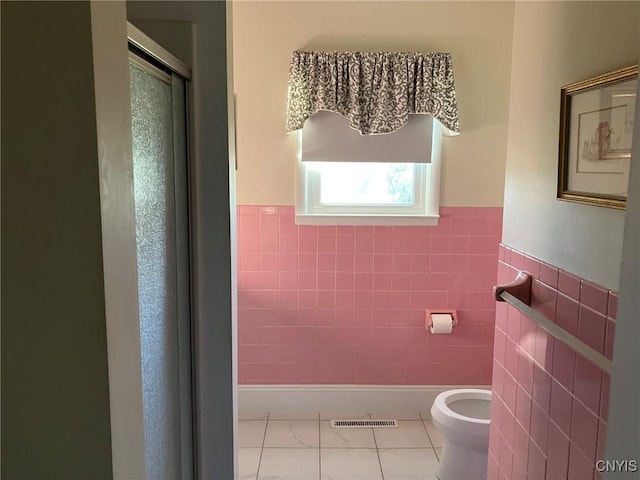 bathroom with tile walls, a stall shower, tile patterned floors, and visible vents