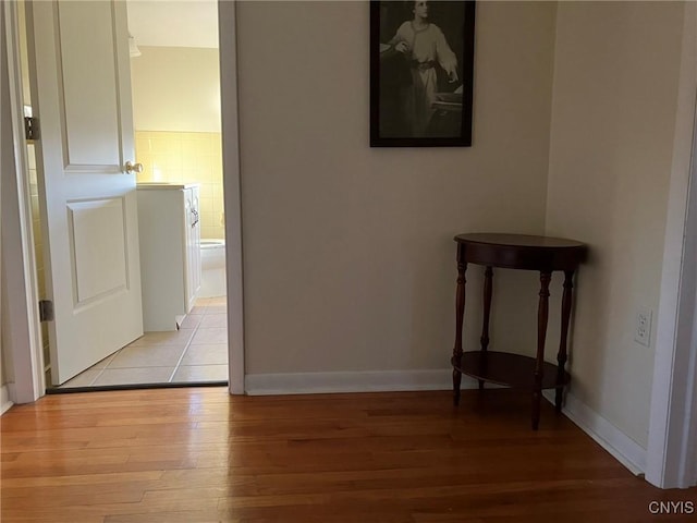 corridor featuring baseboards and light wood-type flooring
