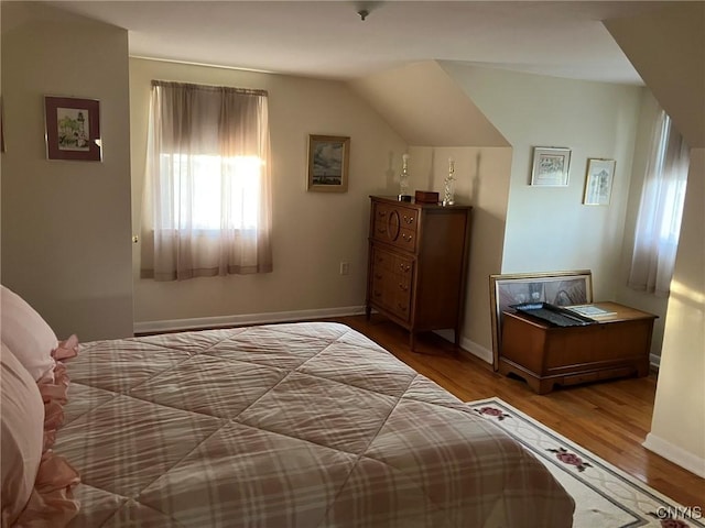bedroom with baseboards, vaulted ceiling, and wood finished floors