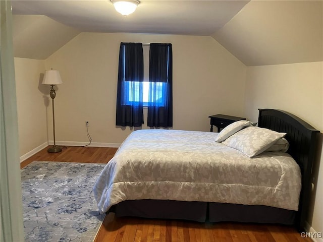 bedroom with baseboards, wood finished floors, and lofted ceiling