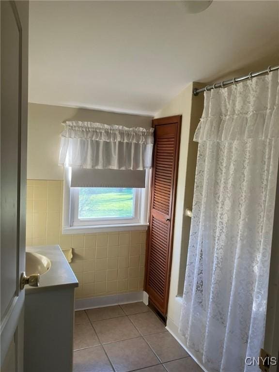bathroom with tile patterned flooring, vanity, and tile walls