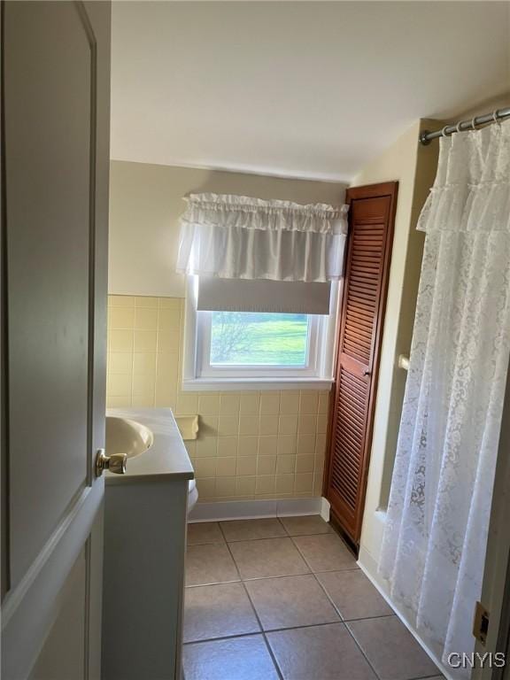 bathroom with tile patterned floors, tile walls, and vanity