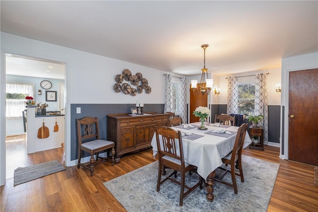 dining area featuring a chandelier, wood finished floors, and a wainscoted wall