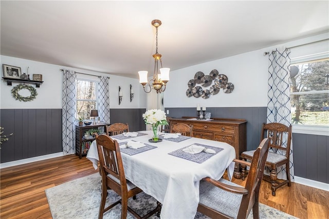dining space featuring a notable chandelier, wainscoting, and wood finished floors