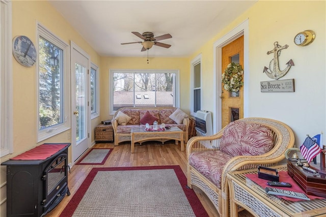 sunroom / solarium featuring heating unit, plenty of natural light, and wood finished floors
