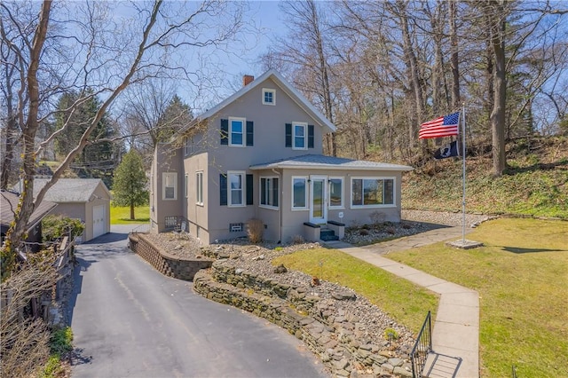 view of front facade featuring a detached garage, stucco siding, a front yard, a chimney, and an outdoor structure