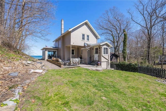 back of house featuring an outdoor living space, a chimney, a lawn, fence, and stucco siding