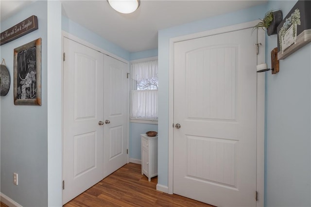 corridor with baseboards and wood finished floors