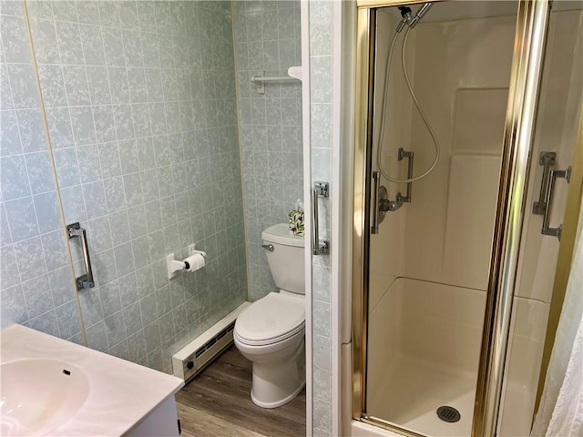 full bathroom featuring wood finished floors, toilet, tile walls, baseboard heating, and a stall shower